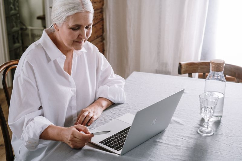 Older woman sitting at a table using a laptop