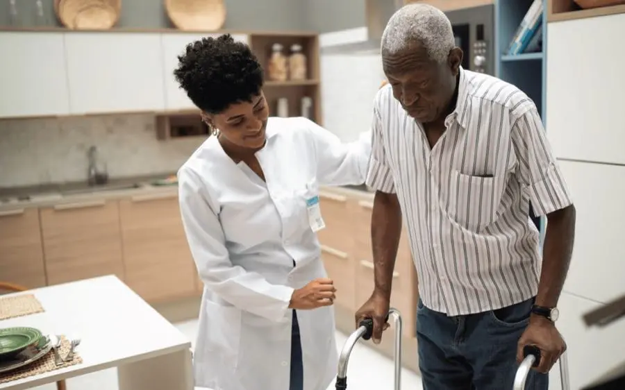 medwell-care-at-home A care worker helps an older man use a walker at home